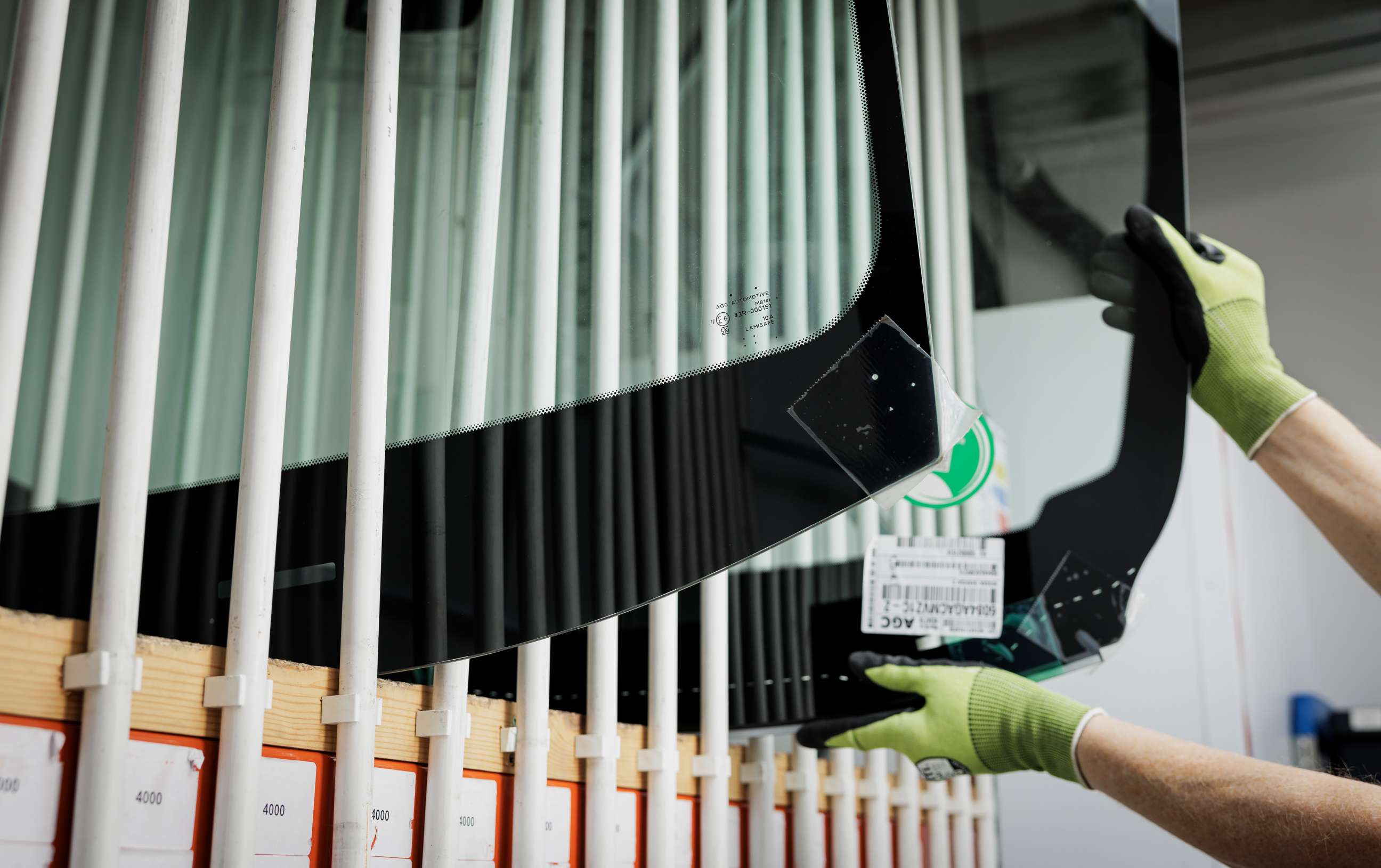Technician lifting windscreen out of racking