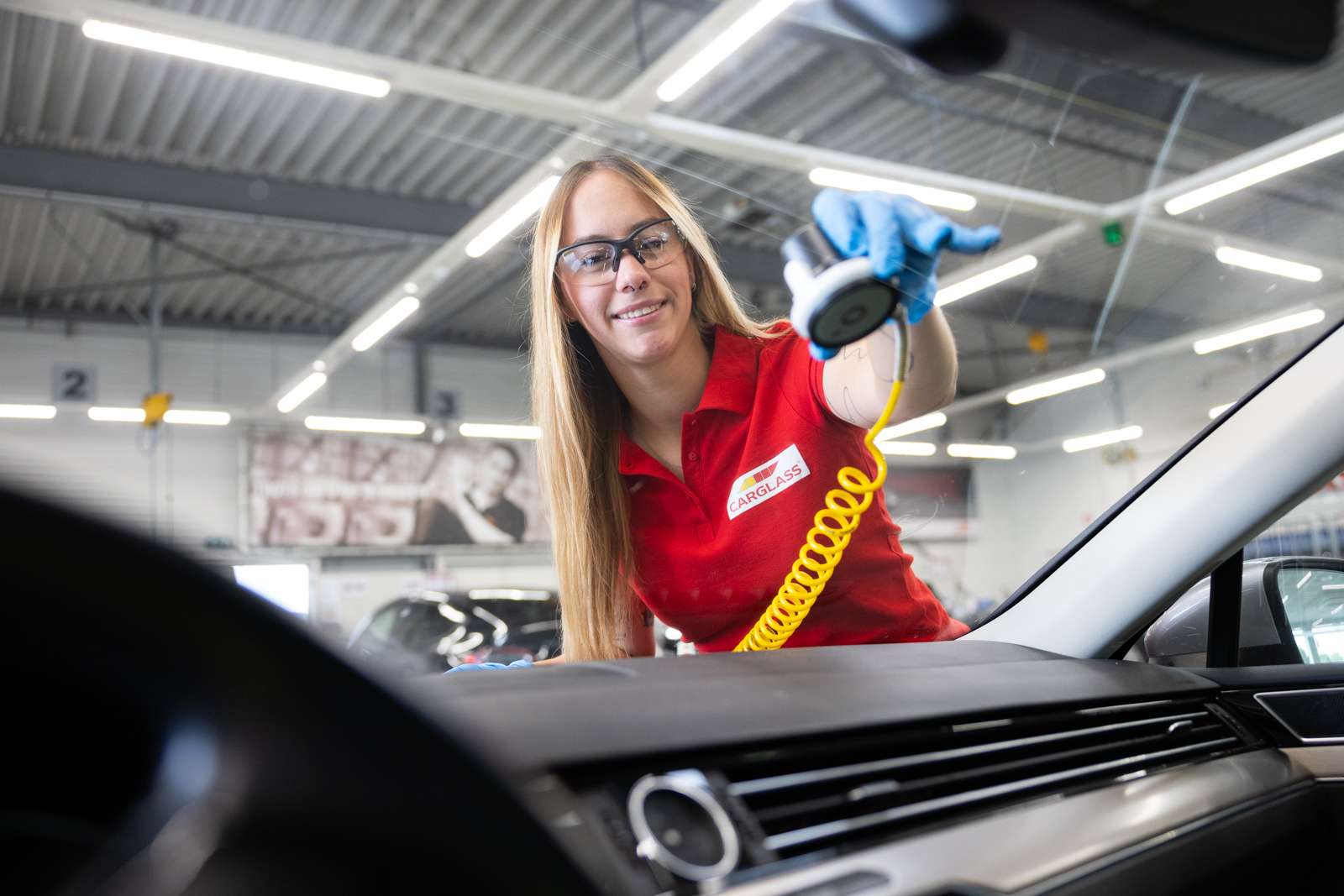 Female technician repairing cracked windscreen glass